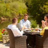 A group of people dining alfresco near a lakeside.