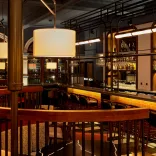 A restaurant in a hotel with bar stools against the fully stocked bar.