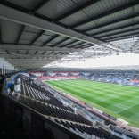 Ground view overlooking the hospitality boxes stand seats and green pitch.