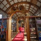A library with panelled ceiling and books on shelves along the hallway.