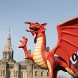 A statue of a Welsh dragon with a castle in the background.