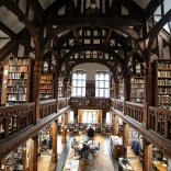 People in a library full of books on upper and lower levels