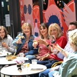 Group of people sitting at dining tables eating and drinking on a food tour.