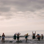 women in bathers running into the sea cheering and laughing