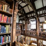 books on shelves floor to ceiling with wooden beams around ceiling