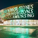 outsideof the wales millennium centre at night with words written into the building lit up