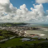 view of Aberystwyth coat with white clouds blue sky and mountains in teh background