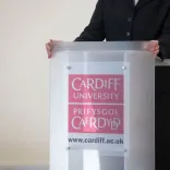 lecturers hands resting on podium wuth Cardiff University bilingual branding
