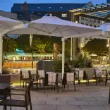 Outdoor terrace with seating, large white parasols and warm ambient lighting