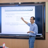 Qingwei Wang pointing to an ESG-focused slide on a screen during a talk in a conference room