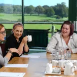 people laughing while in a meeting around the table with the racecourse in the background 