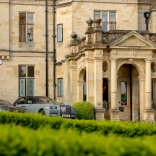 Grand stone country house entrance with classical columns and parked luxury cars Provide your feedback on BizChat
