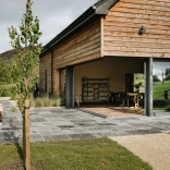 Modern timber-clad venue with open-plan interior and outdoor terrace in a rural landscape setting.