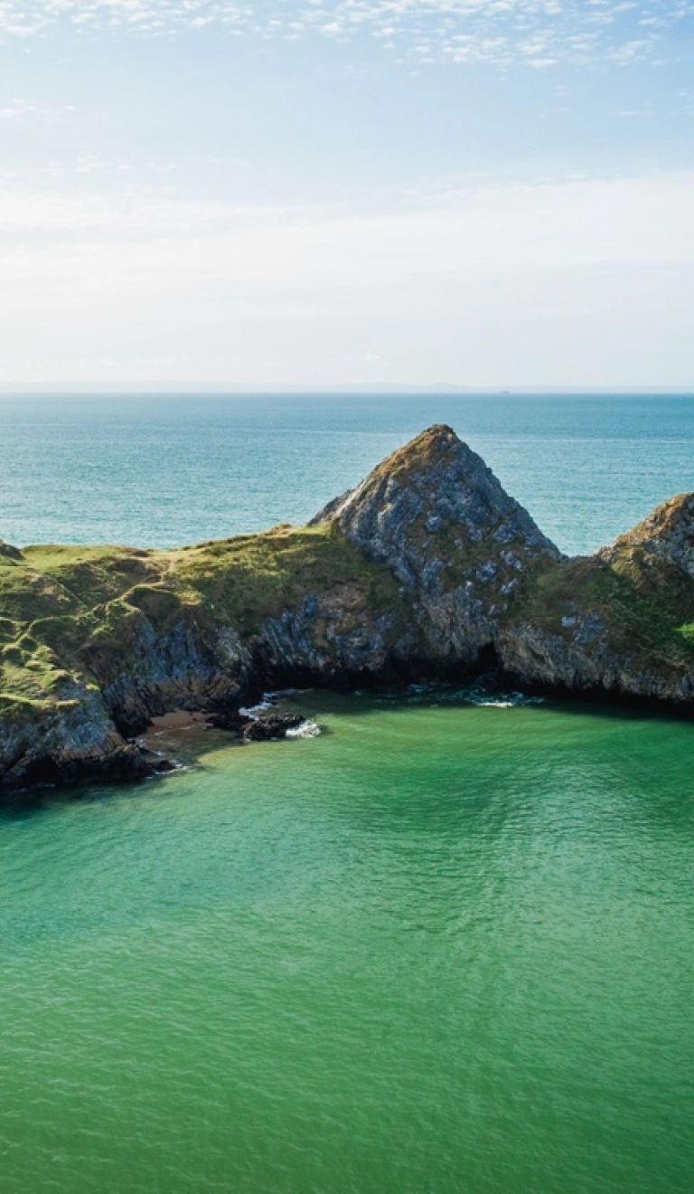 Three cliffs with water and blue sky.