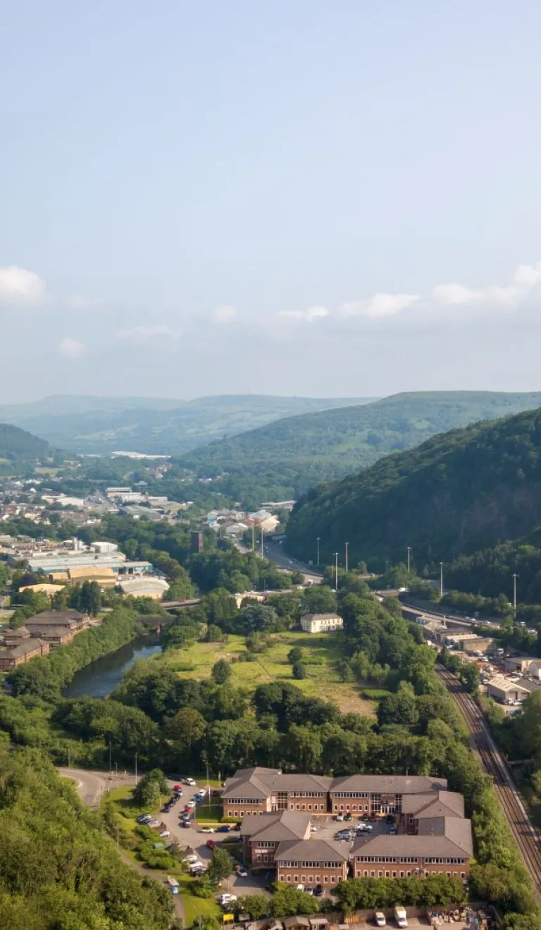 Aerial view of a major road through the valleys with a castle perched on a mountain.