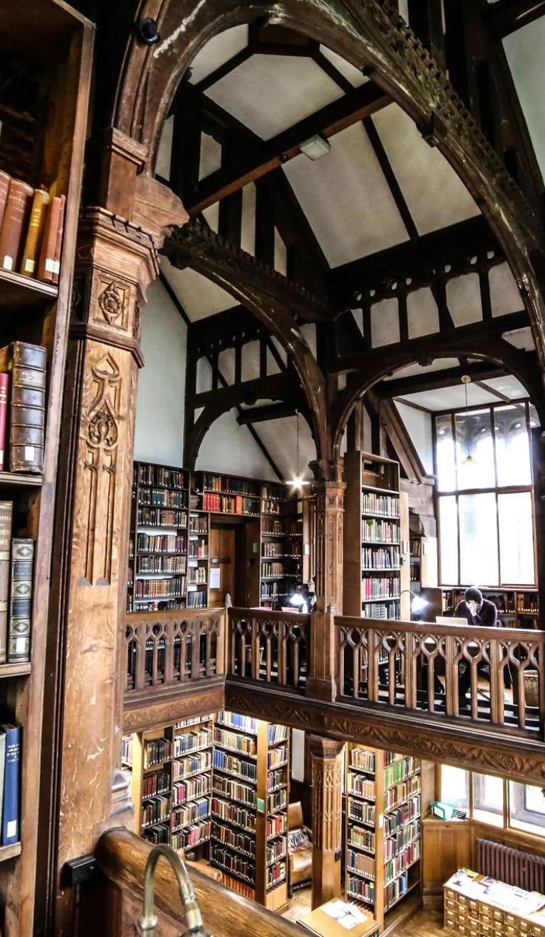 books on shelves floor to ceiling with wooden beams around ceiling