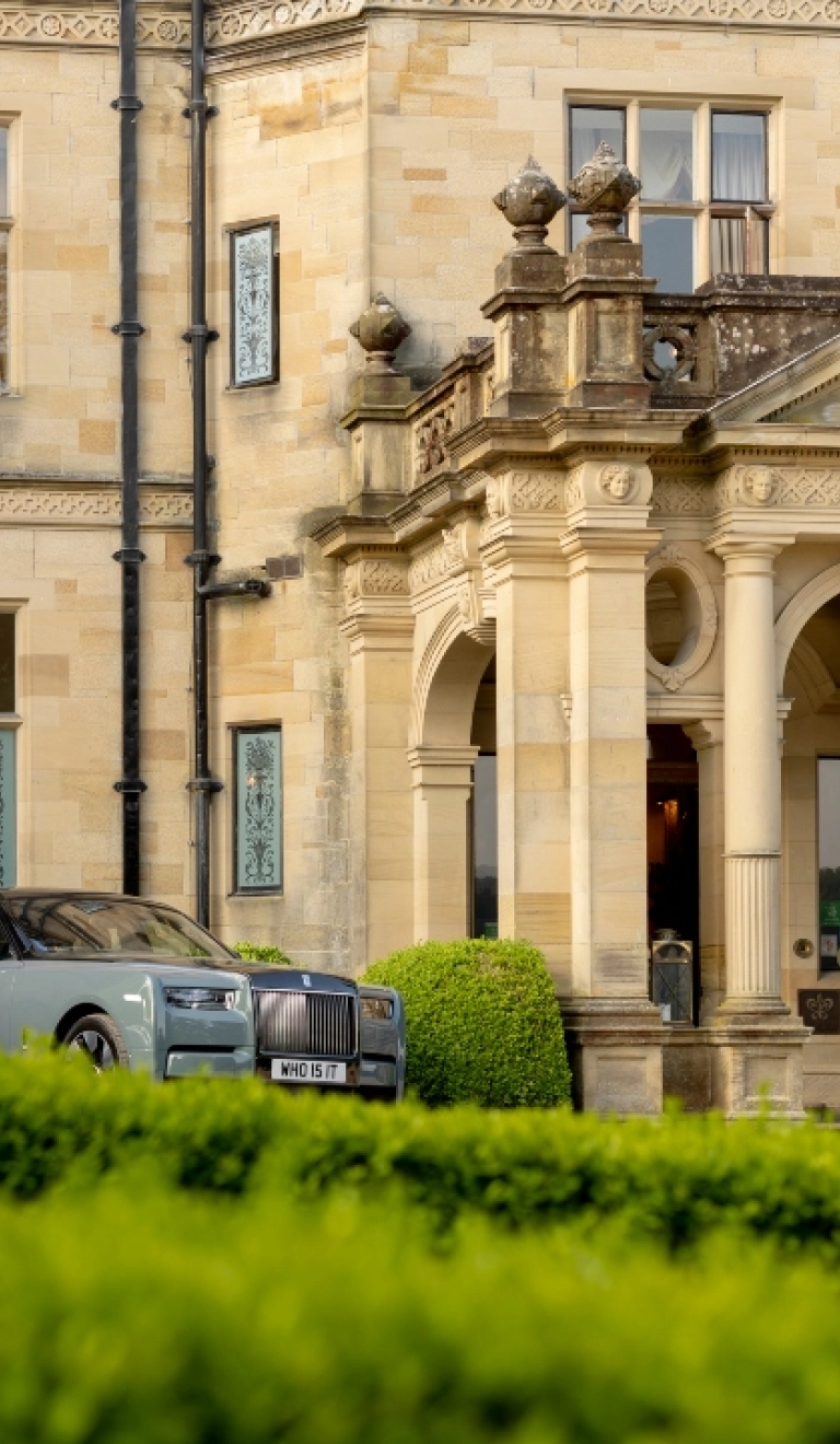 Grand stone country house entrance with classical columns and parked luxury cars Provide your feedback on BizChat